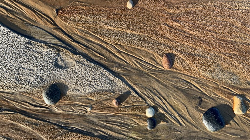 Patterns of sand, stones, water and sun